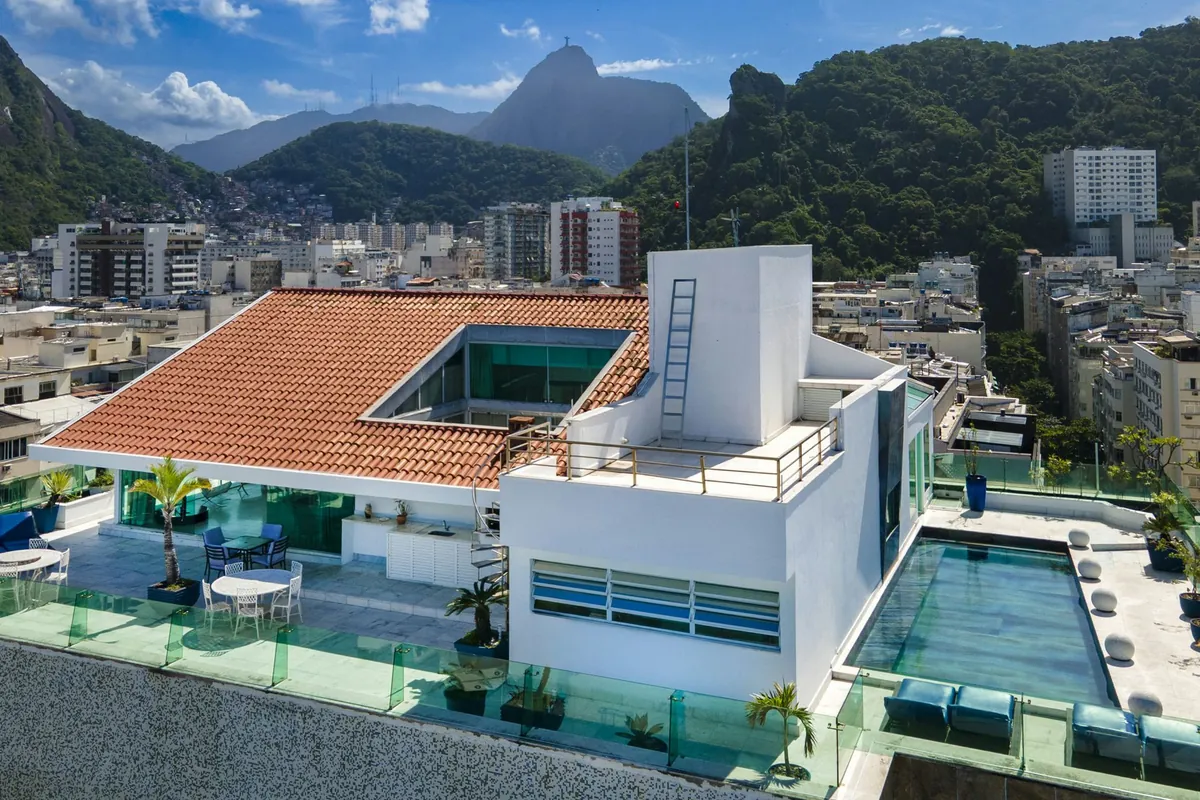 Aerial view of the Copacabana duplex penthouse with its pools and red-tiled roof, the neighborhood and Corcovado behind