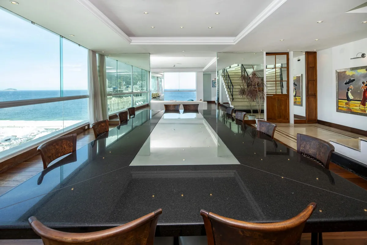 Long dining table in the Copacabana duplex penthouse with glass walls looking over the beach and the sea