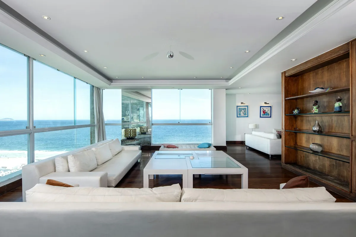 Living room of the Copacabana duplex penthouse with white sofas and floor-to-ceiling windows over Copacabana beach