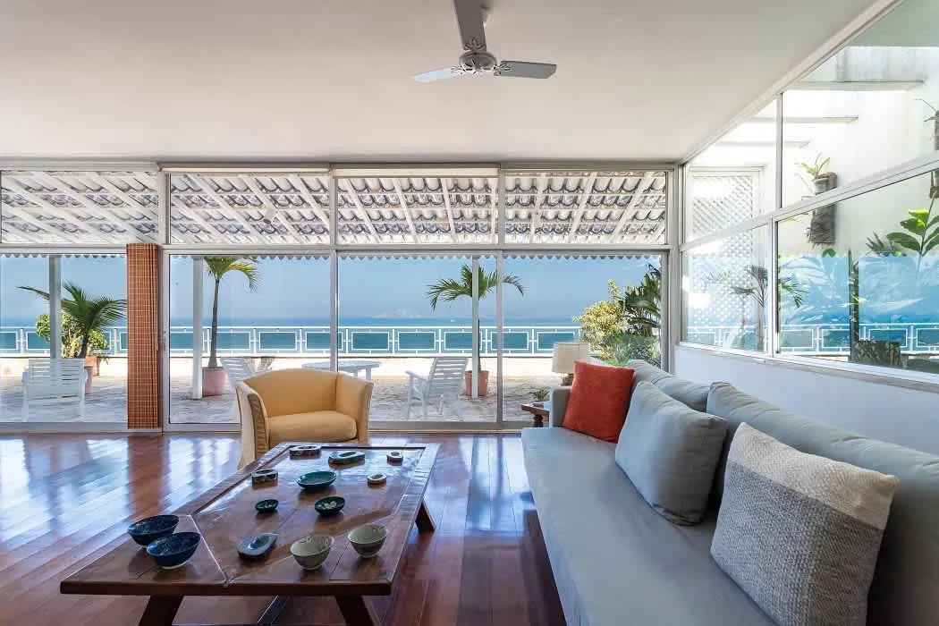 Living room of the Ipanema Beach Linear Penthouse with sofas, a coffee table and glass doors open to the terrace and the sea