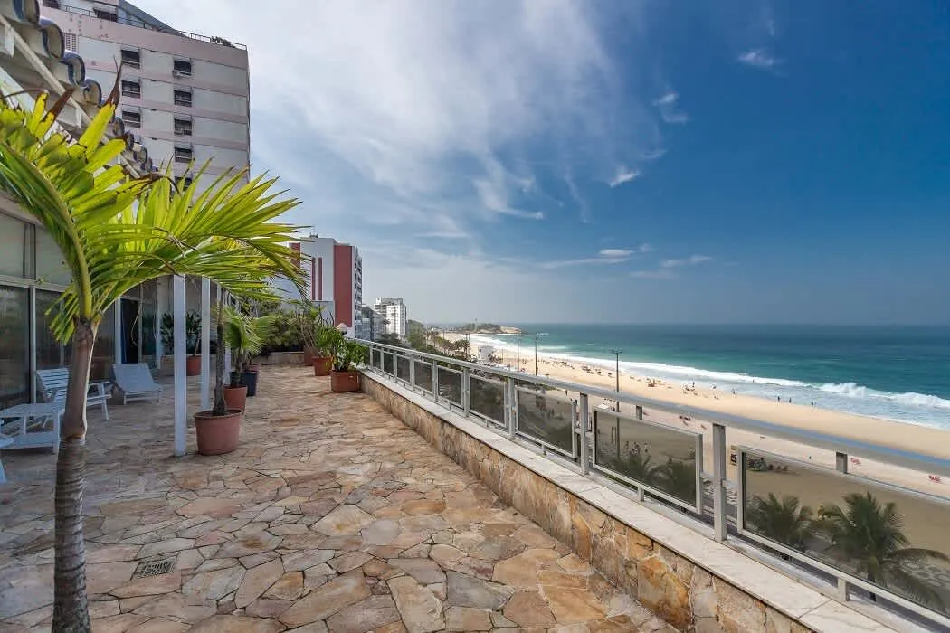 The long terrace of the Ipanema Beach Linear Penthouse running above the beach, with palms and the ocean
