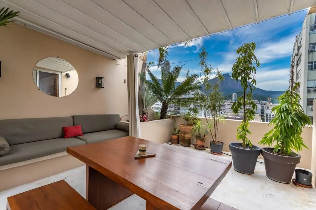 Terrace of the Ipanema two-suite penthouse with plants, an outdoor sofa and a view of the mountains