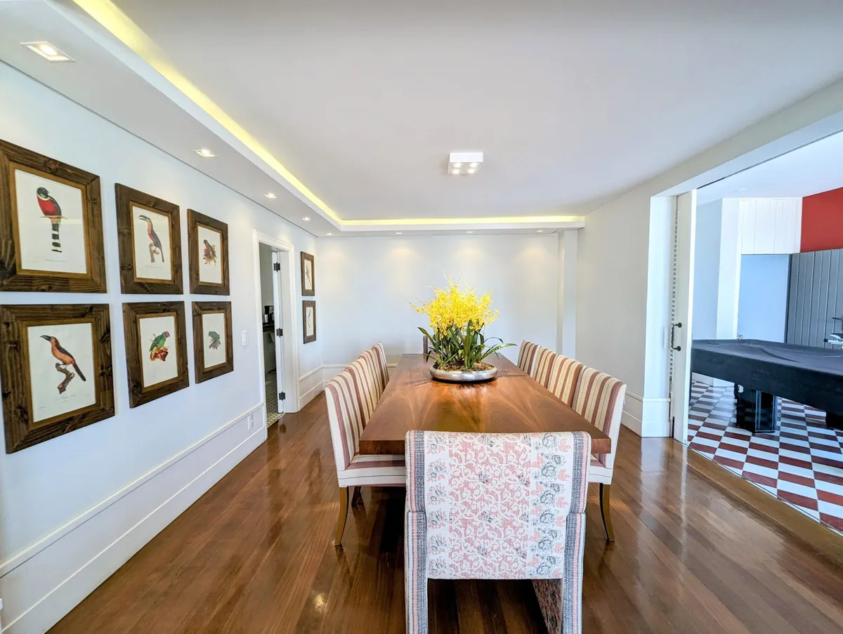 Dining room of a Santa Teresa house with a long table, yellow flowers and framed botanical prints