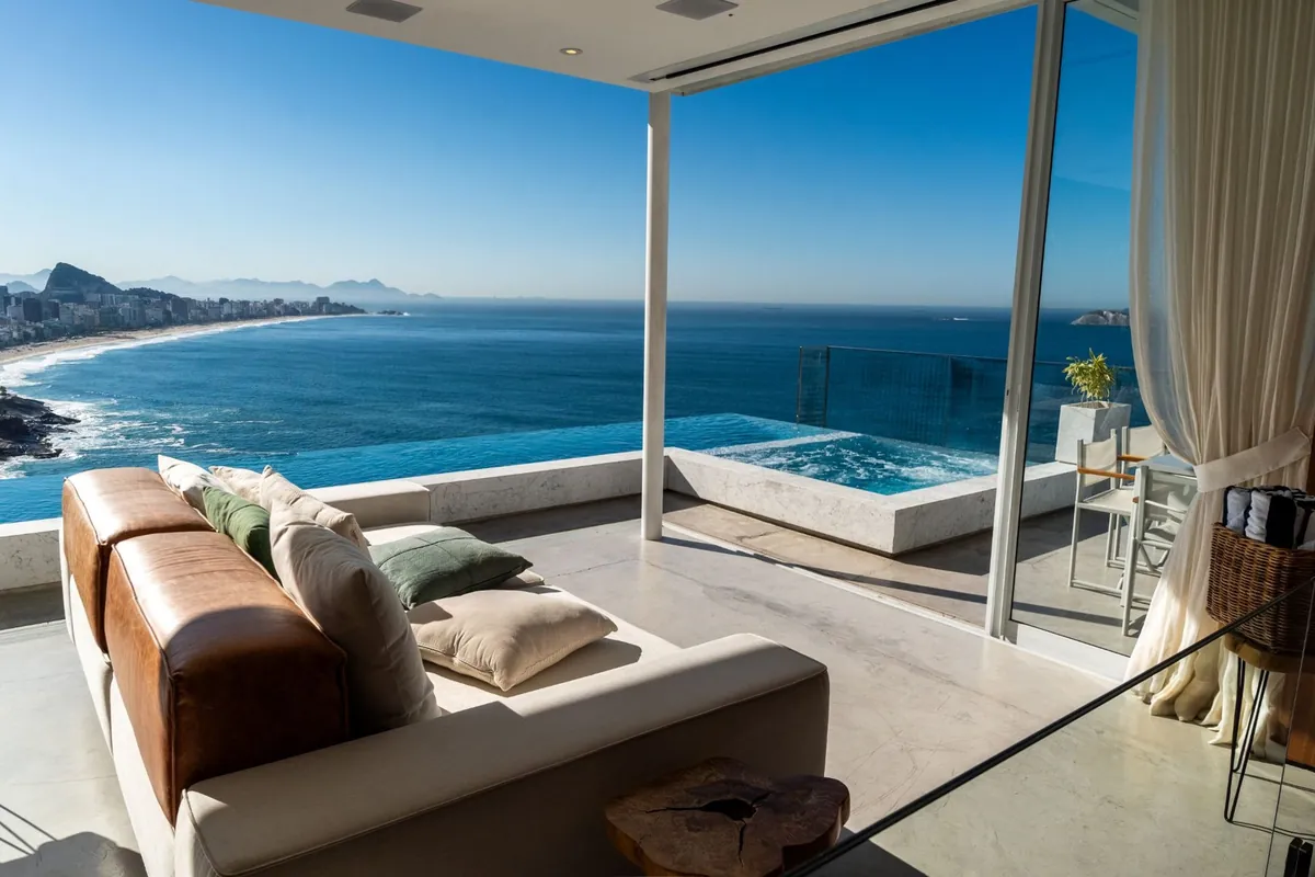 Living room of the Vidigal duplex penthouse with a leather sofa and glass walls opening to a pool terrace and the sea