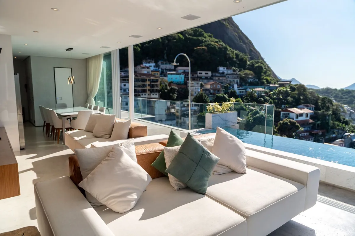 Outdoor sofa on the terrace of the Vidigal duplex penthouse with the hillside and the sea beyond the glass rail